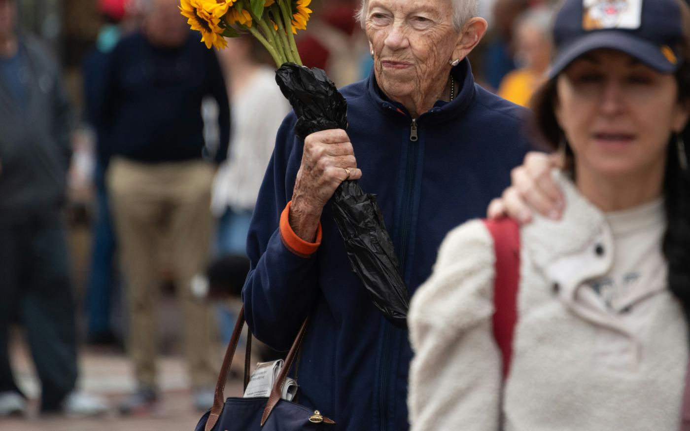 A man holding a bouquet of sunflowers while walking down a street by Joseph Corl courtesy of Unsplash.