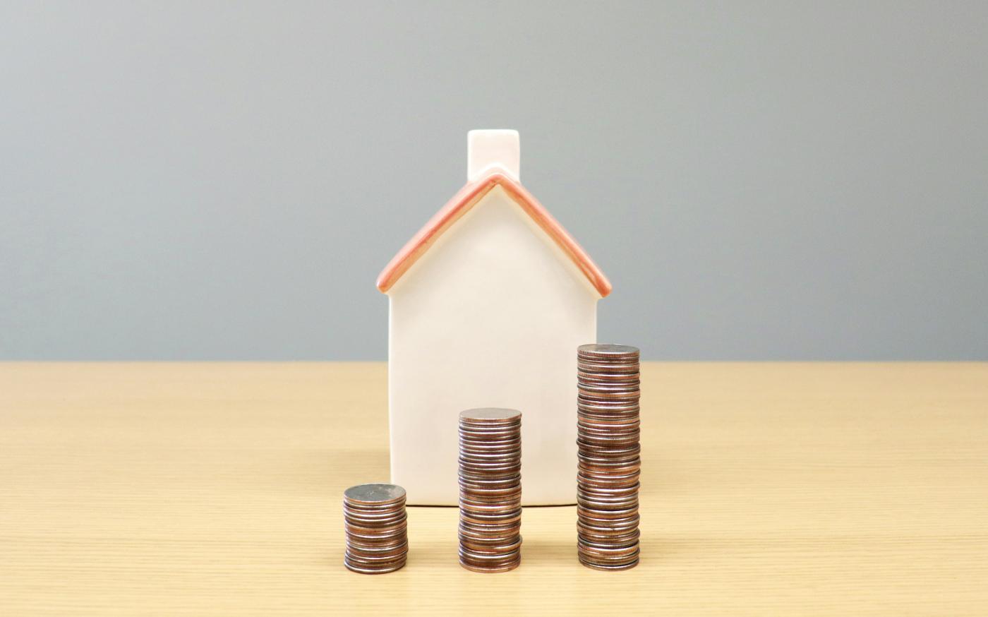 a house and stacks of coins on a table by BuyandRent Homes courtesy of Unsplash.