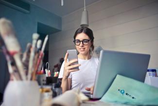 woman in white shirt using smartphone by bruce mars courtesy of Unsplash.