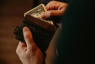 person getting 1 U.S. dollar banknote in wallet by Allef Vinicius courtesy of Unsplash.